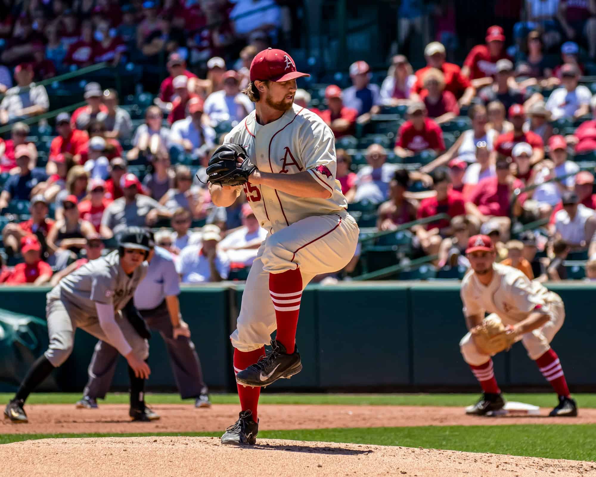 Baseball pitcher in his wind-up with a crowd in the stands