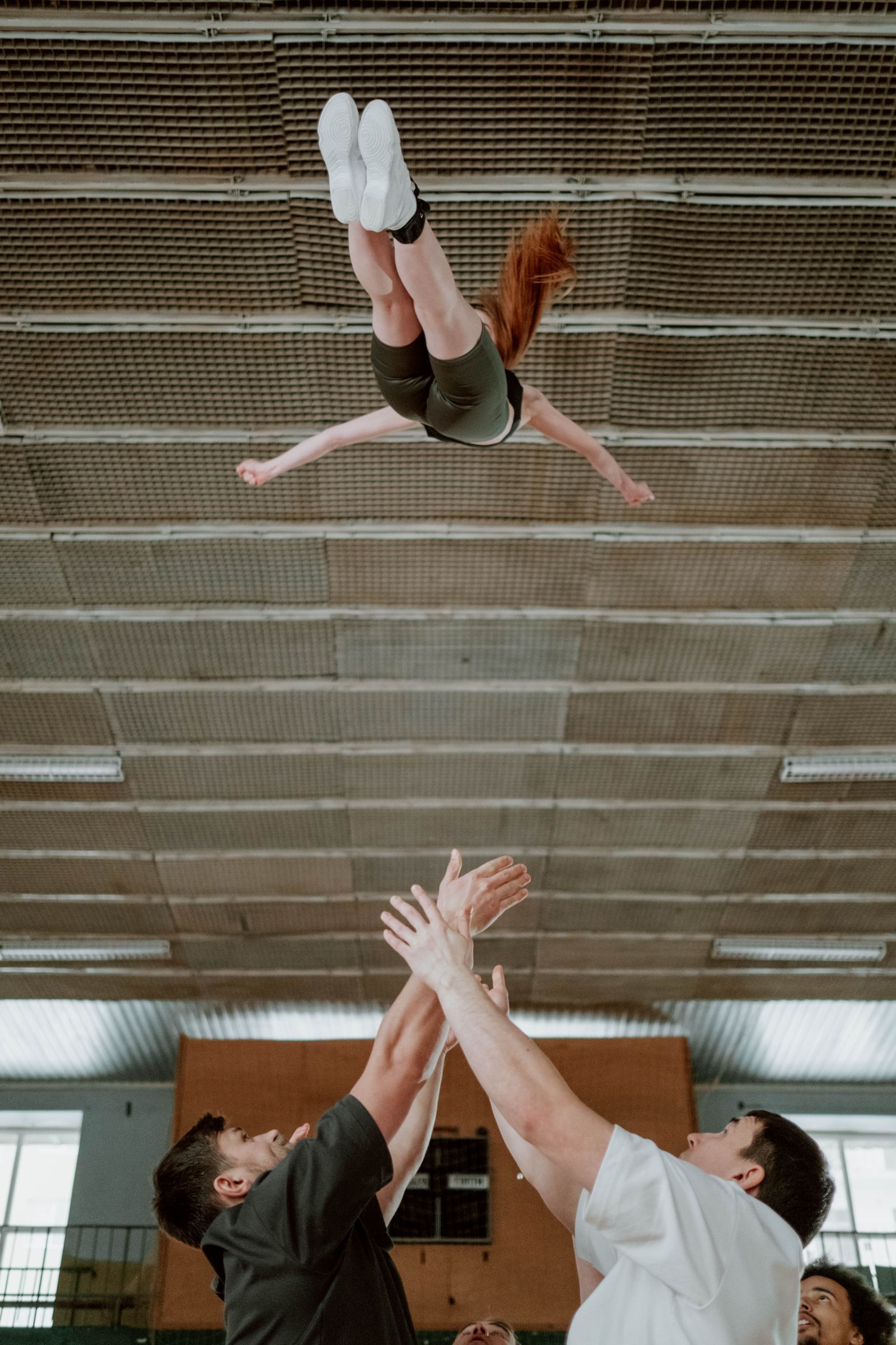 Cheerleader flyer in the air during a stunt, seen from below