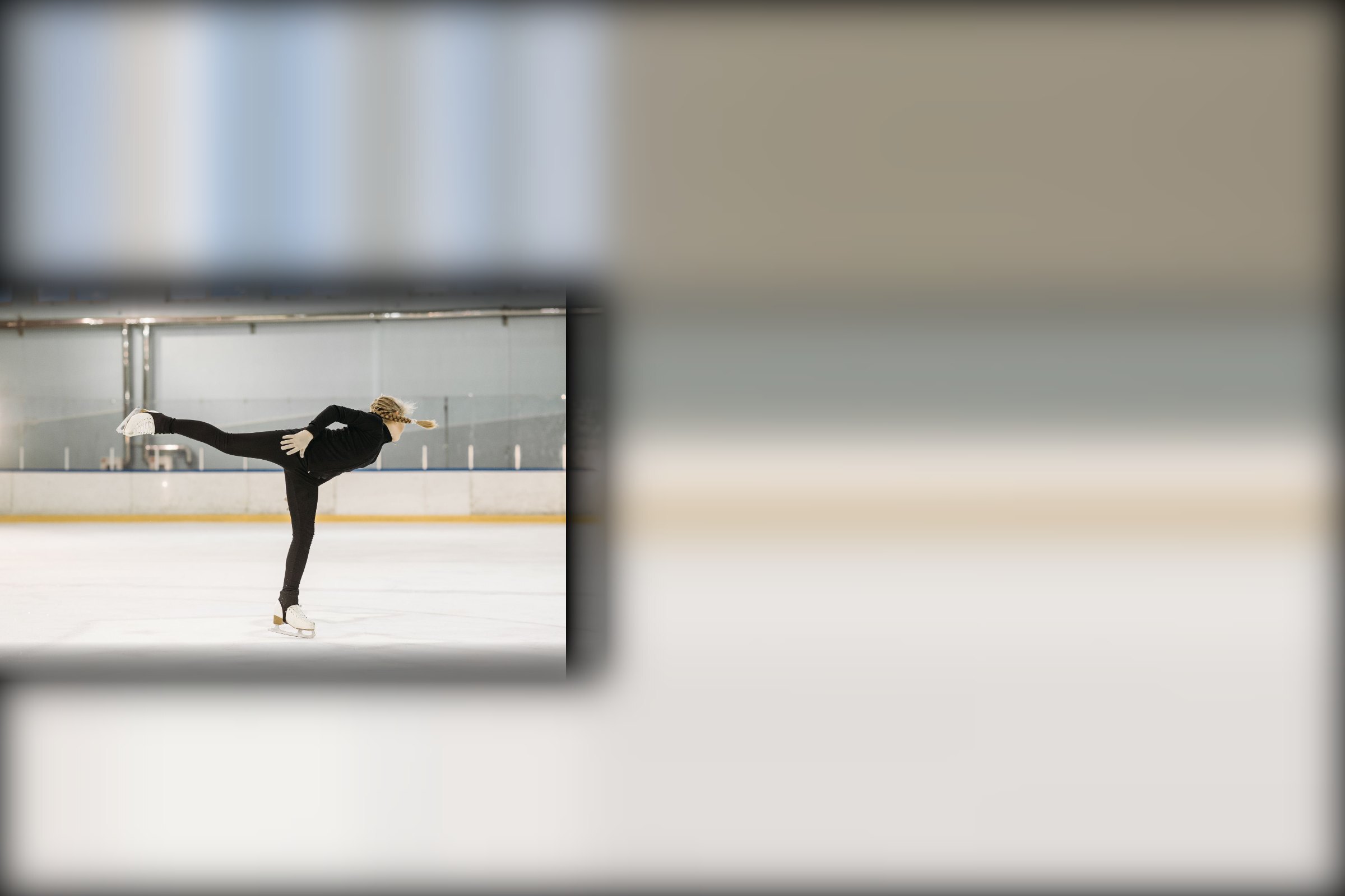 Figure skater holding a spiral position on an indoor ice rink