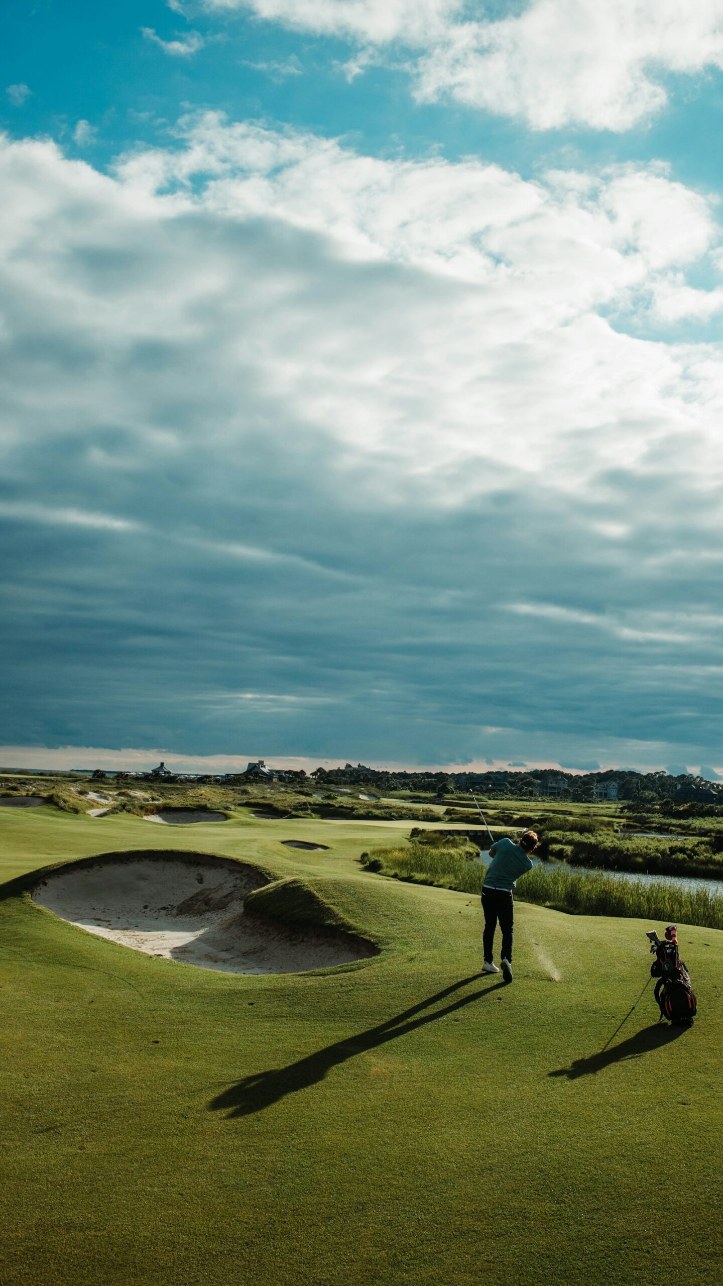 Golfer finishing a swing on a links-style golf course under a dramatic sky